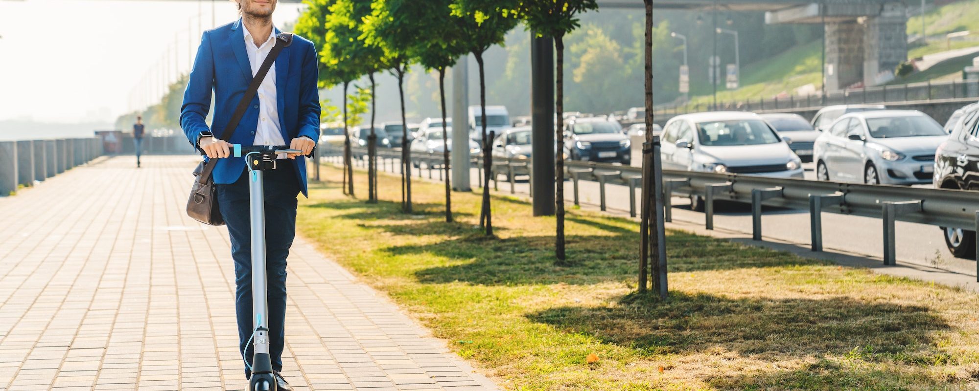 Young businessman riding electric scooter on road in city while there traffic. Ecology concept