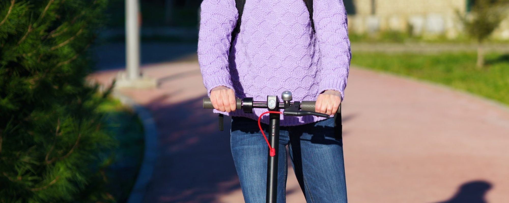 Young woman in her twenties riding an electric scooter using helmet